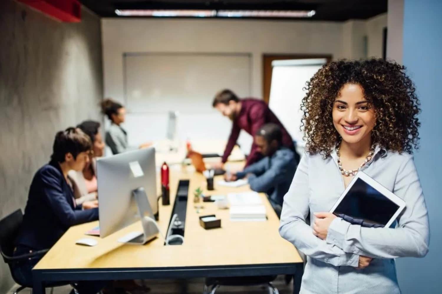 Mulher em sala de reunião com pessoas ao fundo